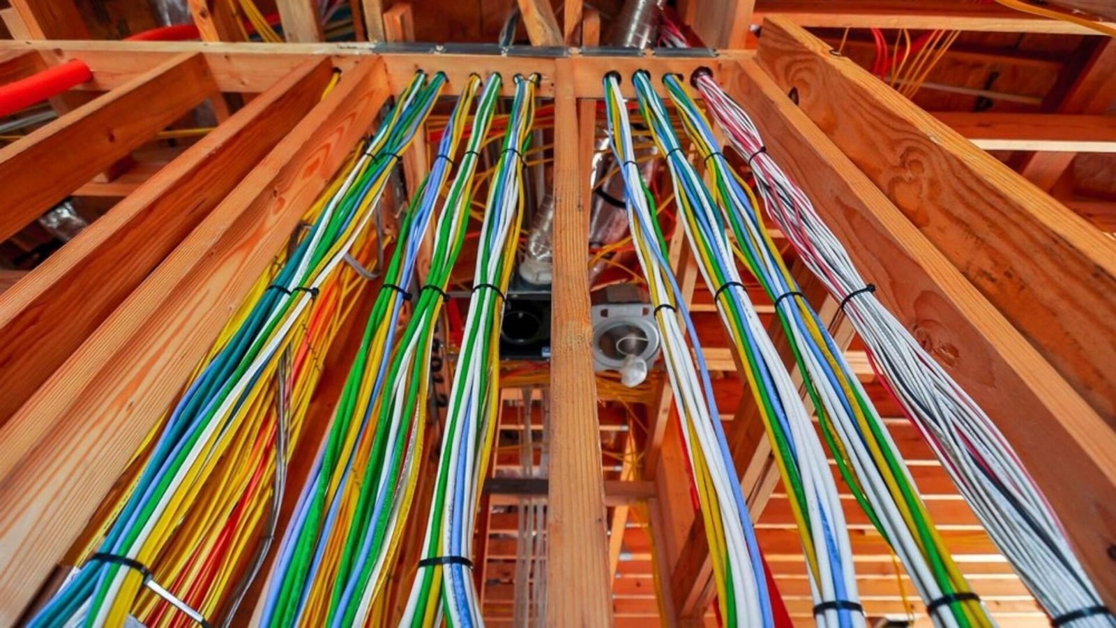 Color-coded low-voltage wiring fanned across new construction framing