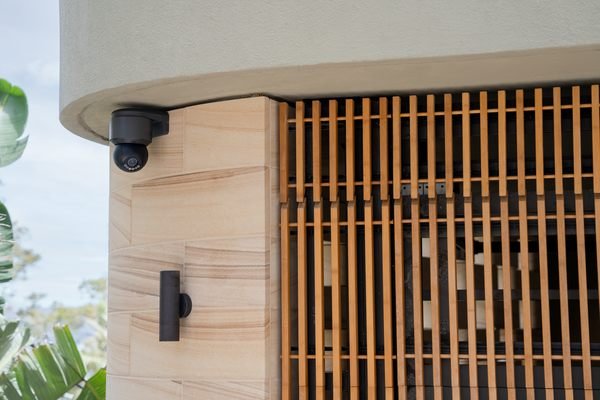 A compact security camera mounted on a slatted wood wall
